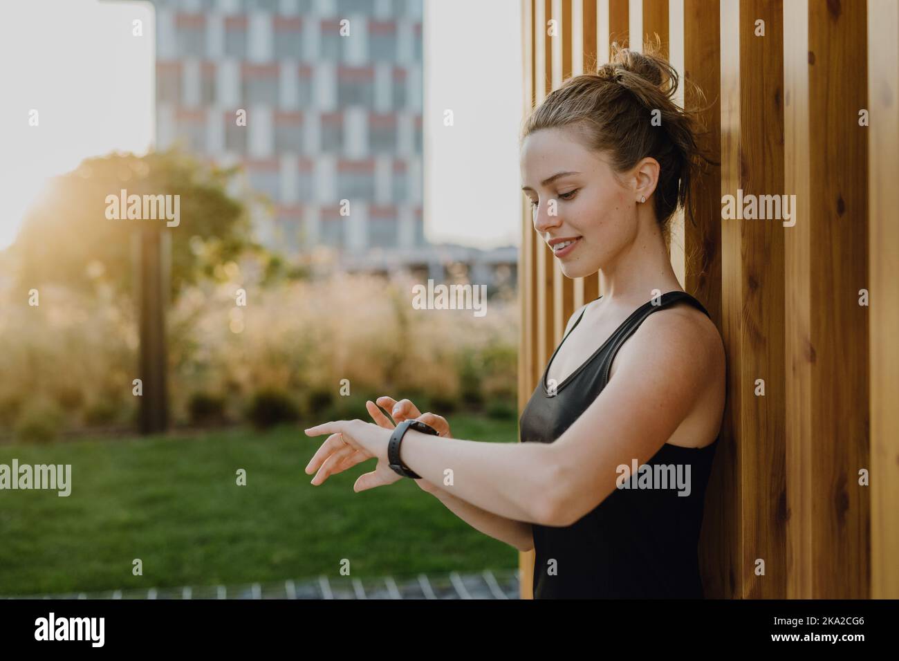 Giovane donna che controlla smartwatch in città, preparandosi per la corsa, stile di vita sano e concetto di sport. Foto Stock