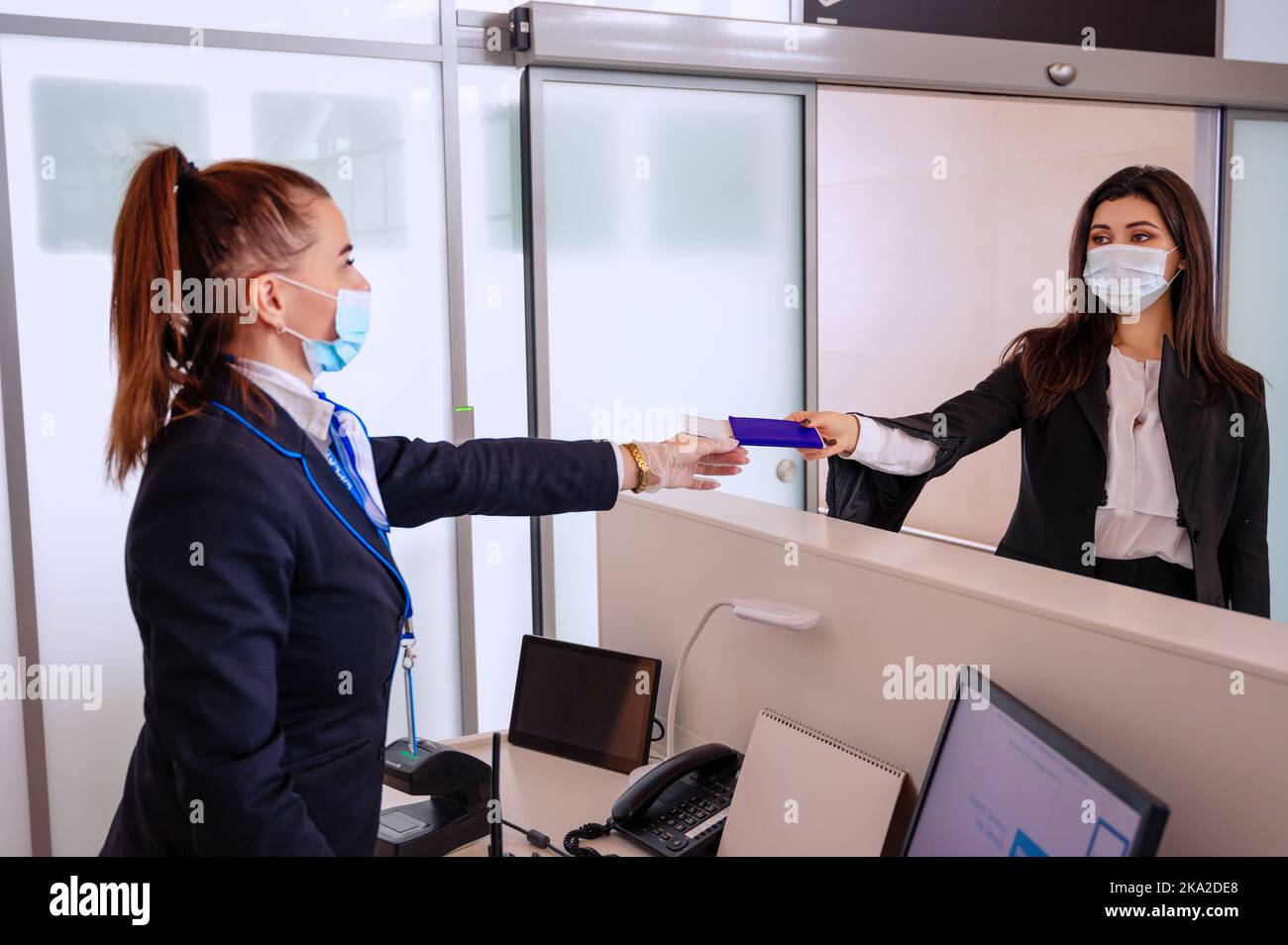 Passeggero che fornisce i suoi documenti per il check-in al gestore dell'aeroporto al banco Foto Stock