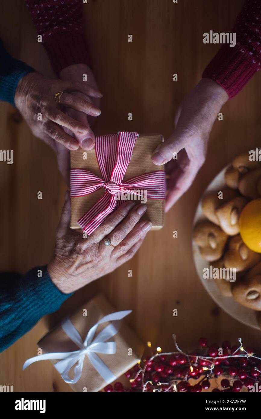 Vista dall'alto della tavola di Natale con decorazioni e mani che danno regali. Foto Stock