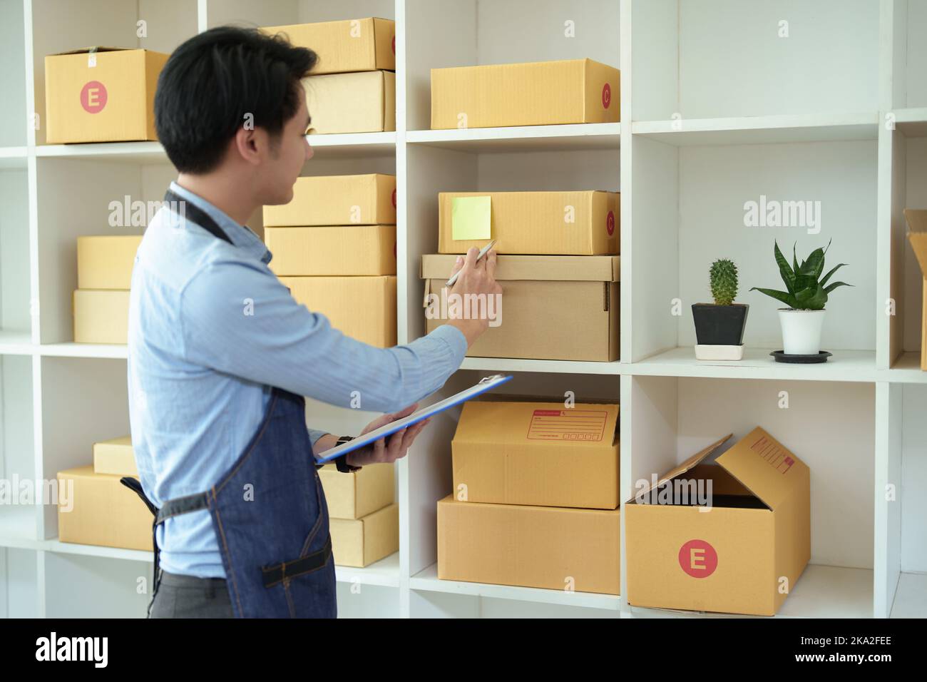 Un ritratto di una piccola startup, un proprietario di PMI, un imprenditore asiatico maschio che controlla gli ordini per organizzare il prodotto prima di imballare i prodotti nel Foto Stock