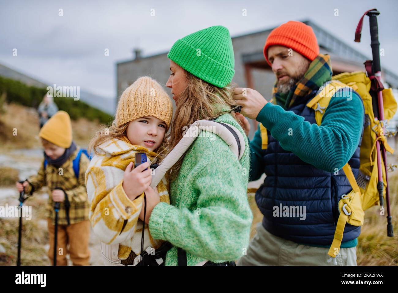 L'uomo aiuta sua moglie con la loro figlia stanca, dandola in portatore bambino, durante l'escursione autunnale in montagna. Foto Stock