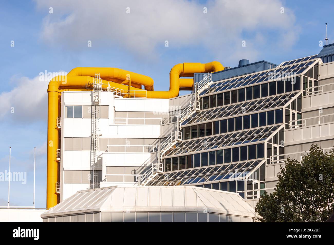 Strano edificio con grandi tubi di riscaldamento gialli per mantenere caldi gli appartamenti residenziali. Foto Stock