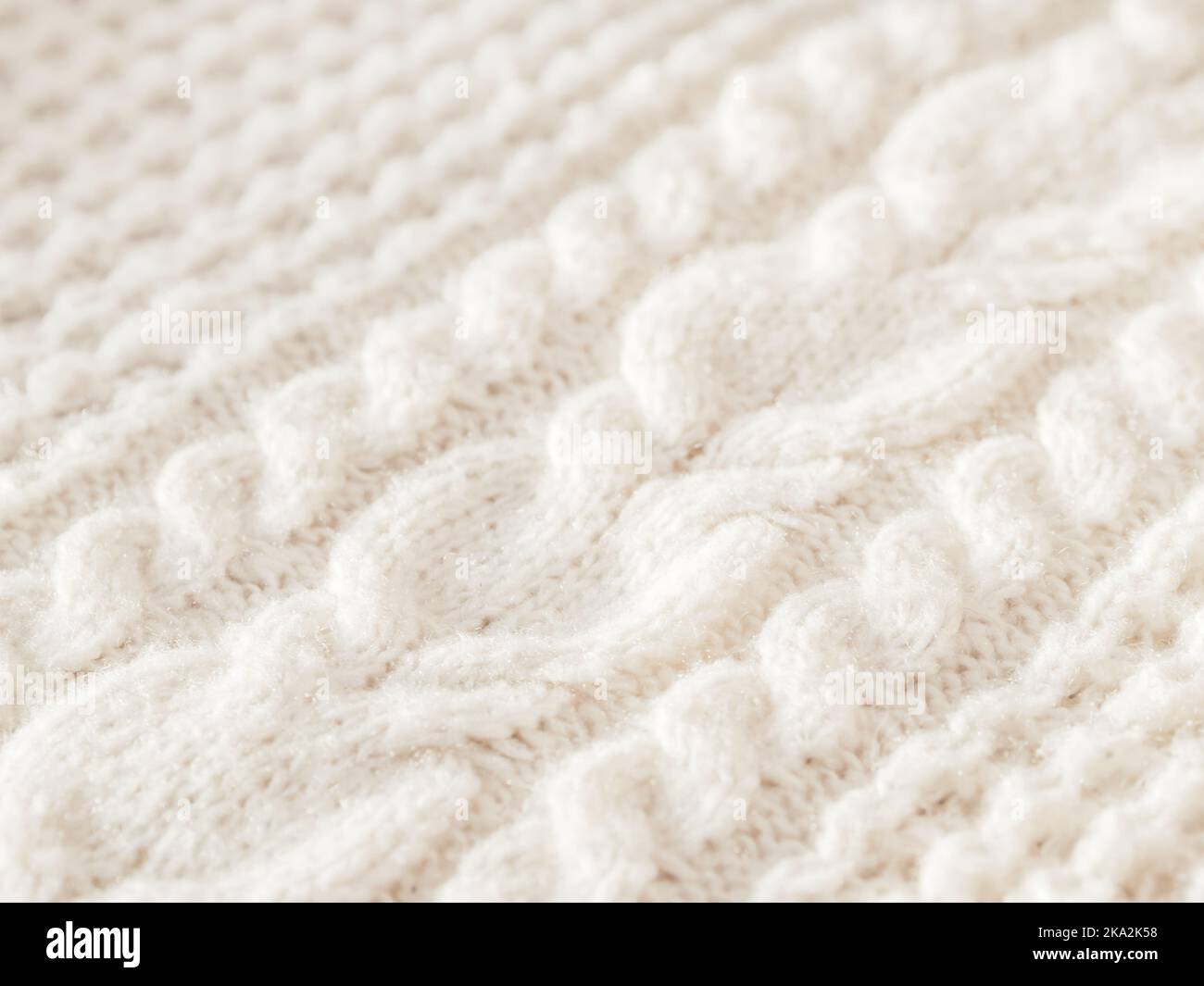Maglione a maglia a cavo realizzato a mano. Texture di tessuto caldo lavorato a maglia con motivo. Cardigan bianco. Intimo vestito autunnale per un clima sereno. Foto Stock