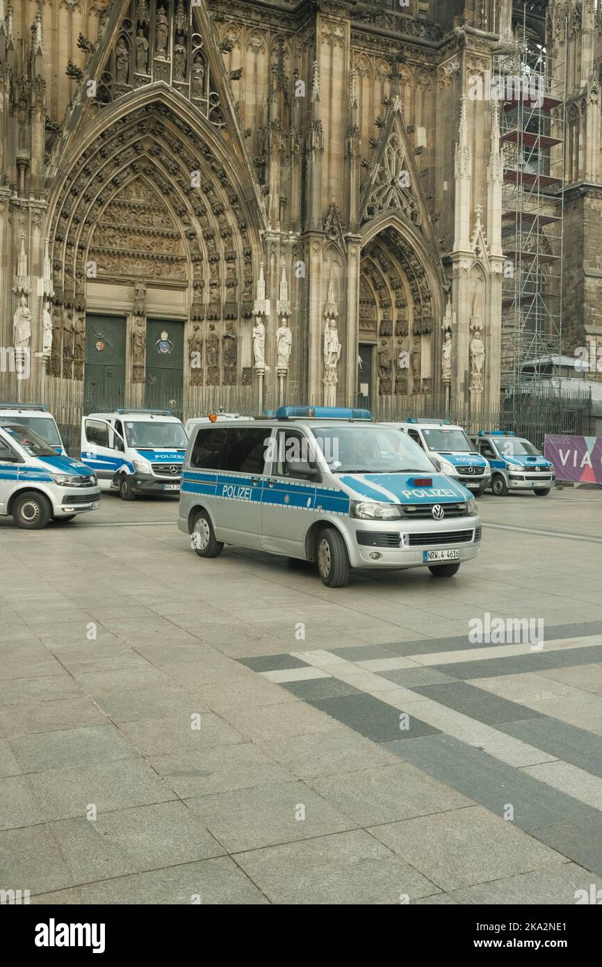 Un autobus di polizia VW Transporter di fronte alla Cattedrale di Colonia con molte auto della polizia in background Foto Stock
