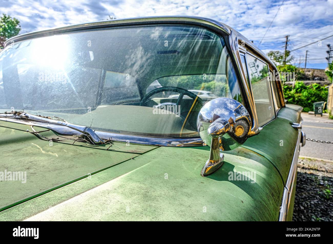 Un primo piano della parte anteriore di un'automobile retrò verde sotto la luce del sole Foto Stock