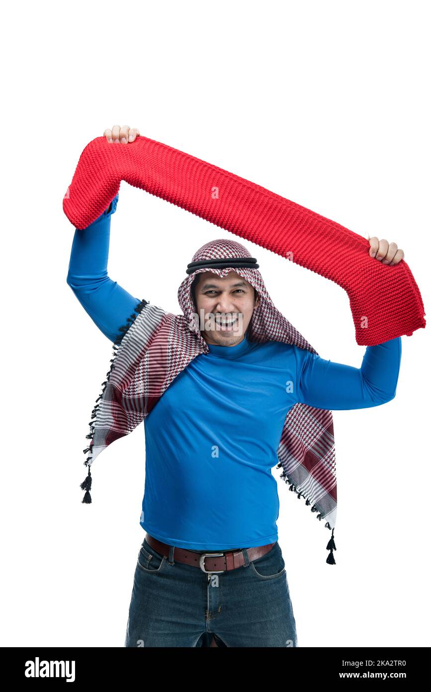 L'uomo asiatico con keffiyeh celebra la vittoria mentre tiene la sciarpa con espressione eccitata isolata su sfondo bianco Foto Stock