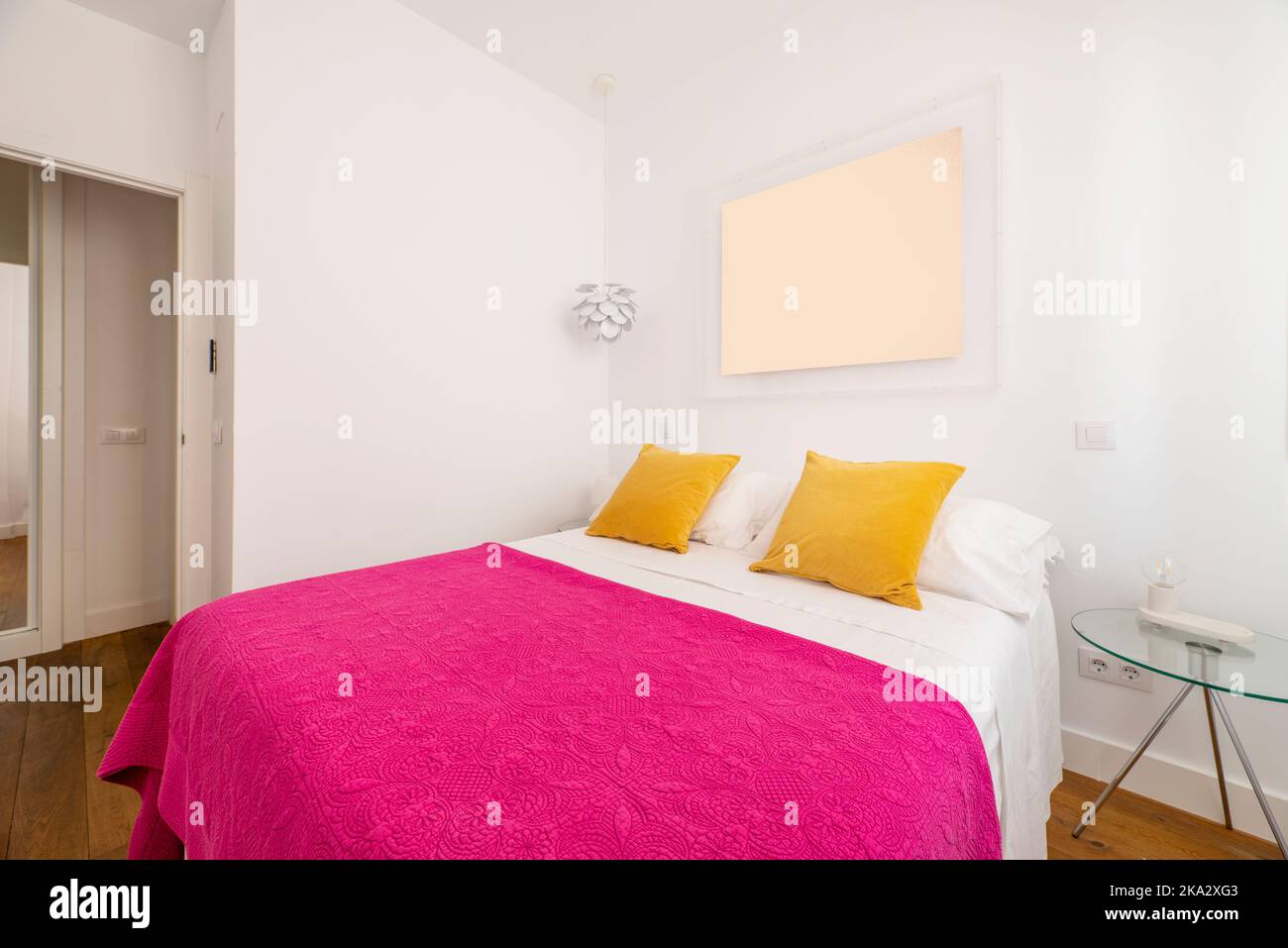 Camera da letto con letto matrimoniale con copriletto rosa luminoso e cuscini gialli Foto Stock