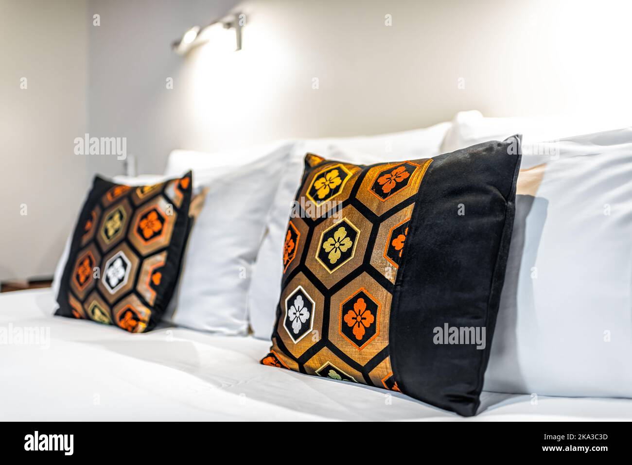 Camera da letto in stile moderno e contemporaneo, casa giapponese in ryokan, con due colorati cuscini in oro giallo e nero su un letto bianco pulito Foto Stock