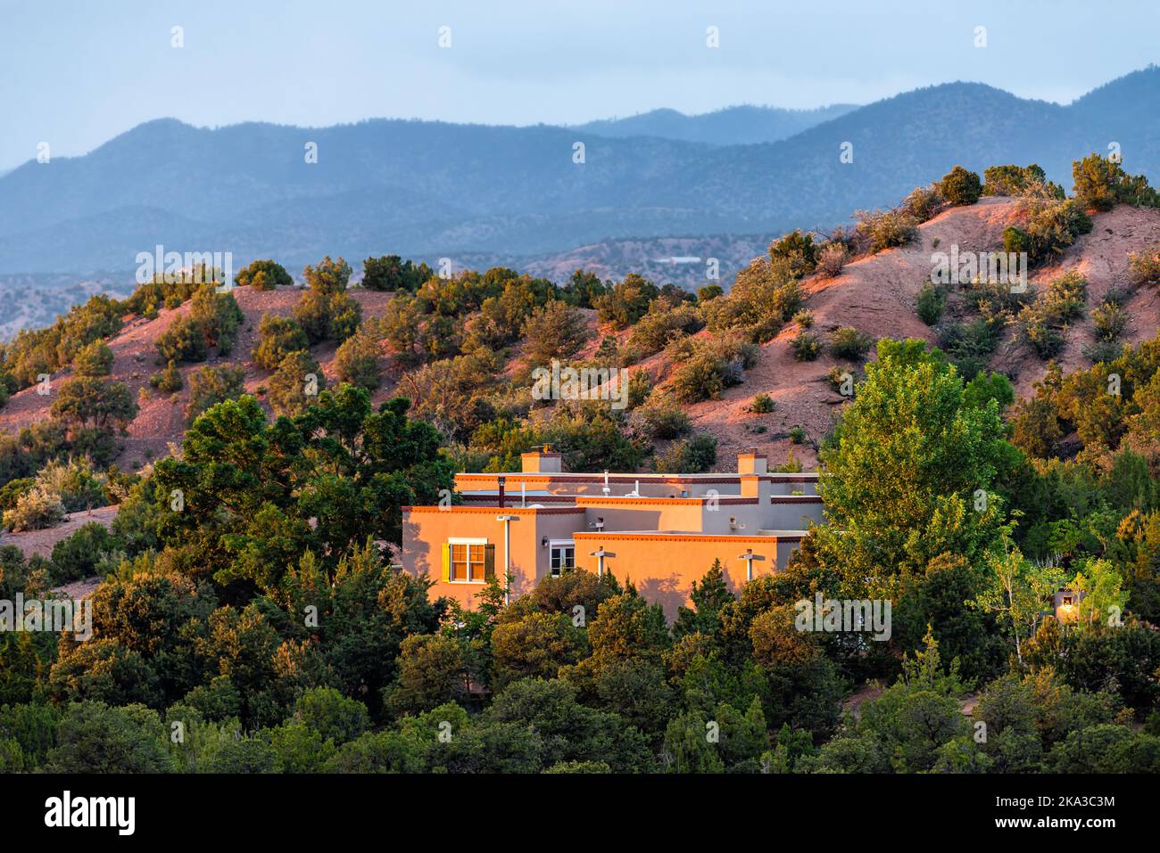 Tramonto a Santa Fe, New Mexico montagne nel quartiere della comunità Tesuque con luce del sole sulla casa con piante verdi e arbusti e cielo blu scuro Foto Stock