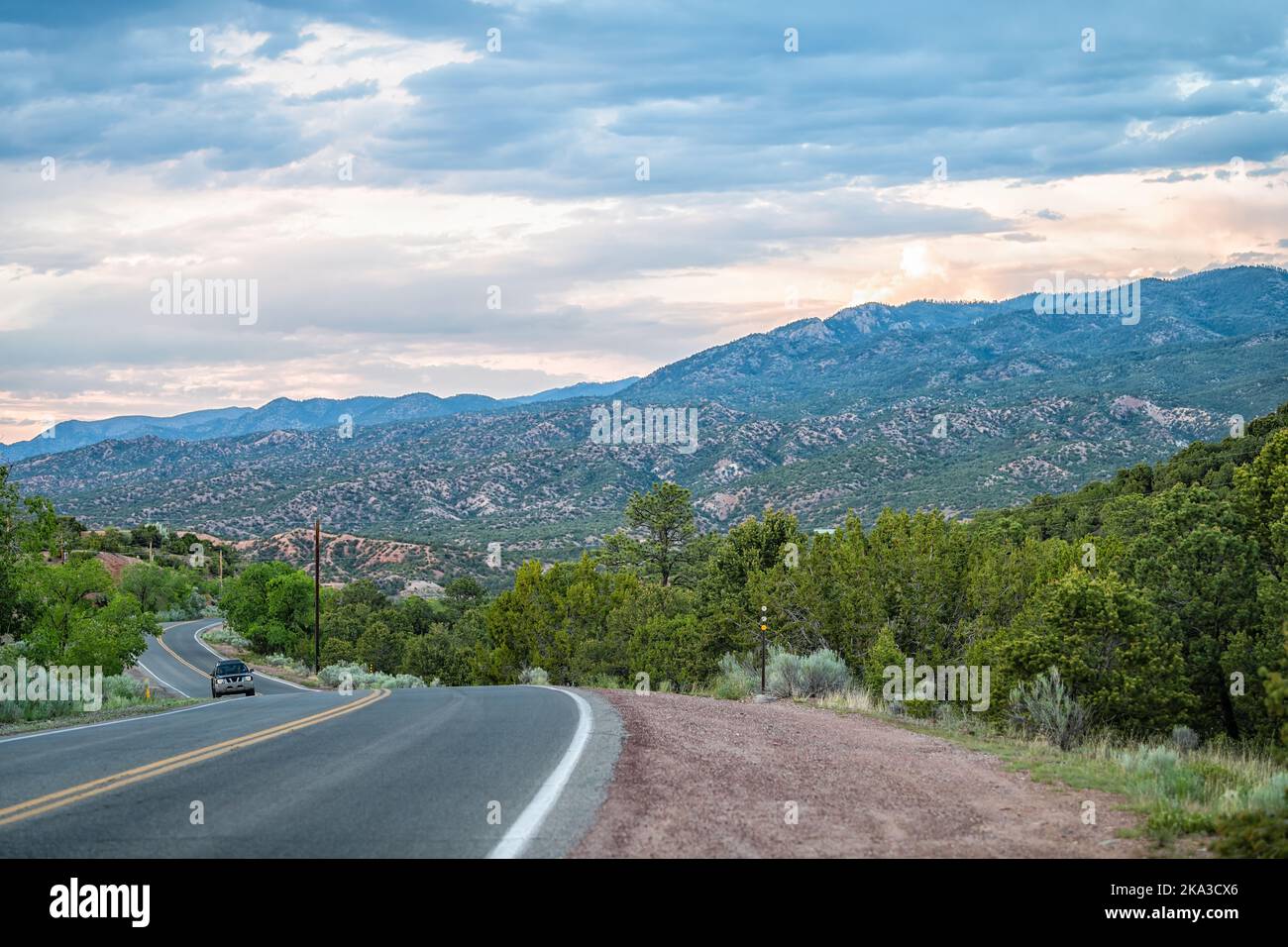 Sangre De Cristo montagne tramonto su Bishops Lodge Road strada a Santa Fe New Mexico con auto guida, luce del sole rosa da parte della comunità residenziale Tesuque Foto Stock