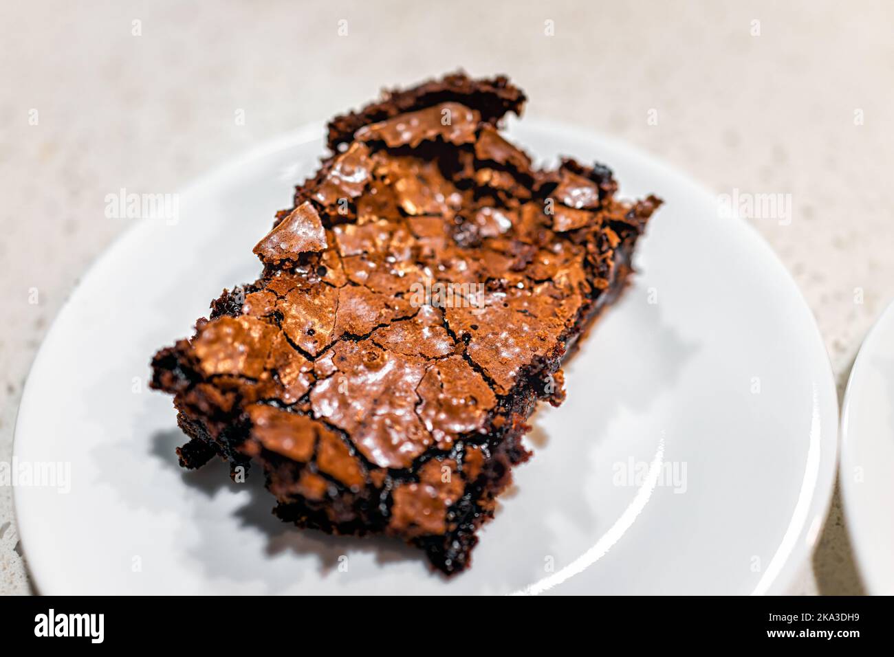 Macro primo piano di una torta di brownie al cioccolato cotta in casa pane da dessert, cibo dolce con briciole sul piatto da cucina su sfondo bianco Foto Stock