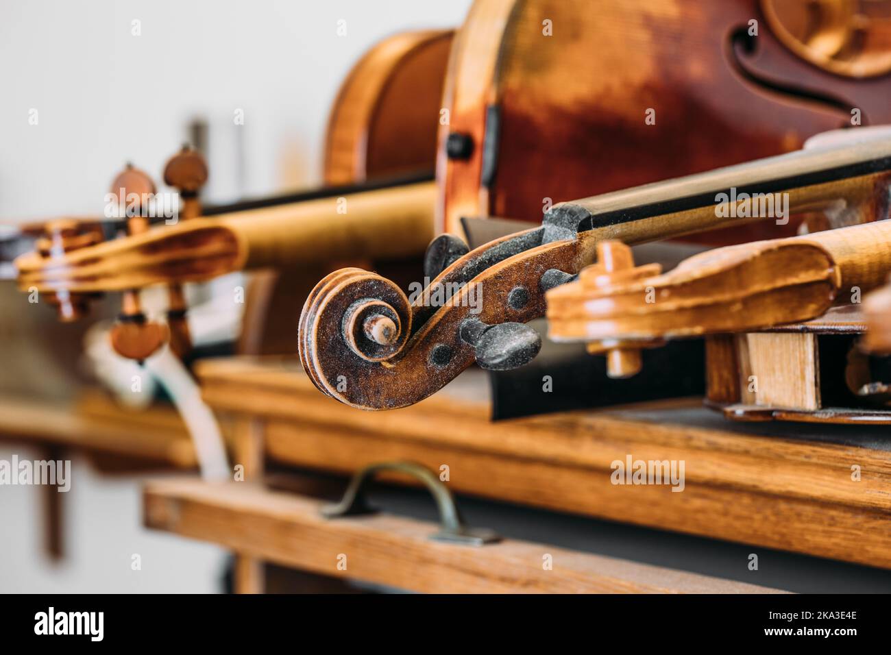 Messa a fuoco morbida di strumento per violino in legno con semplice intaglio a spirale collocato su scaffale in studio luzioso Foto Stock