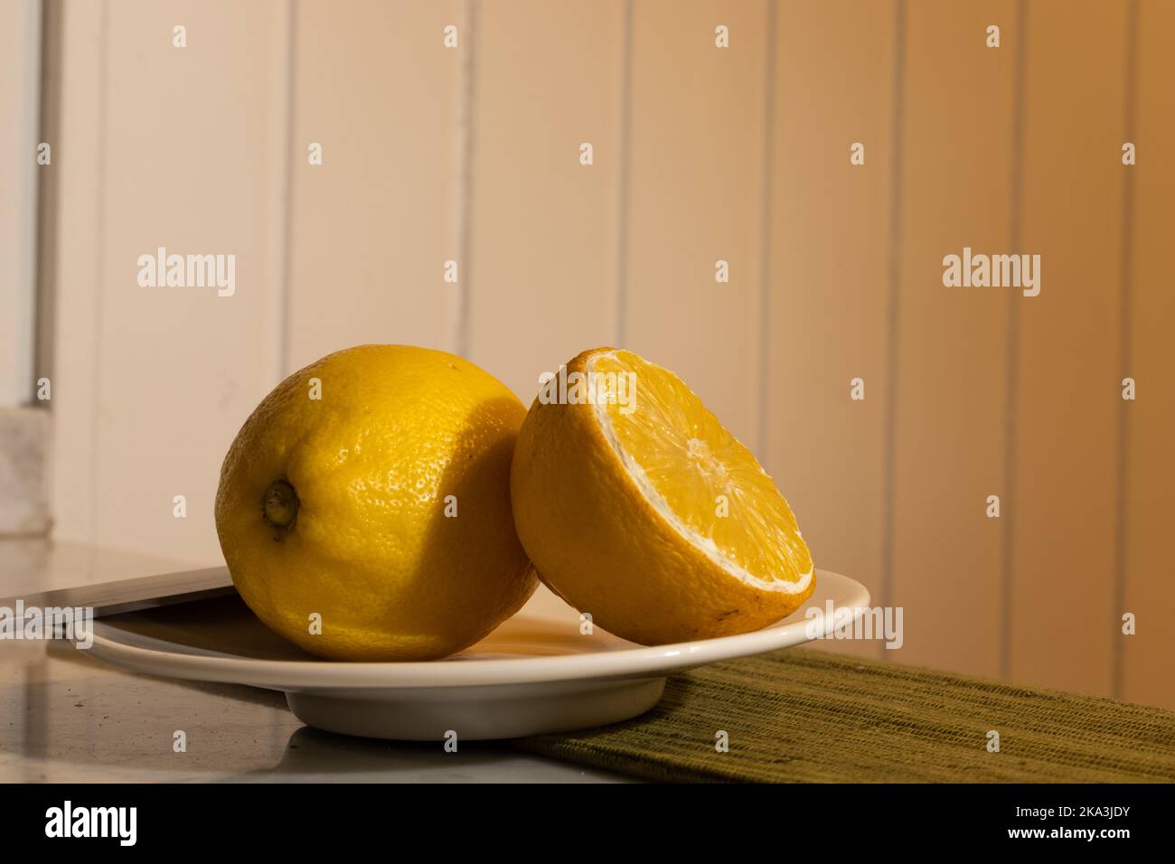 Limone con fondo in legno dipinto di bianco e tovaglia verde scuro Foto Stock