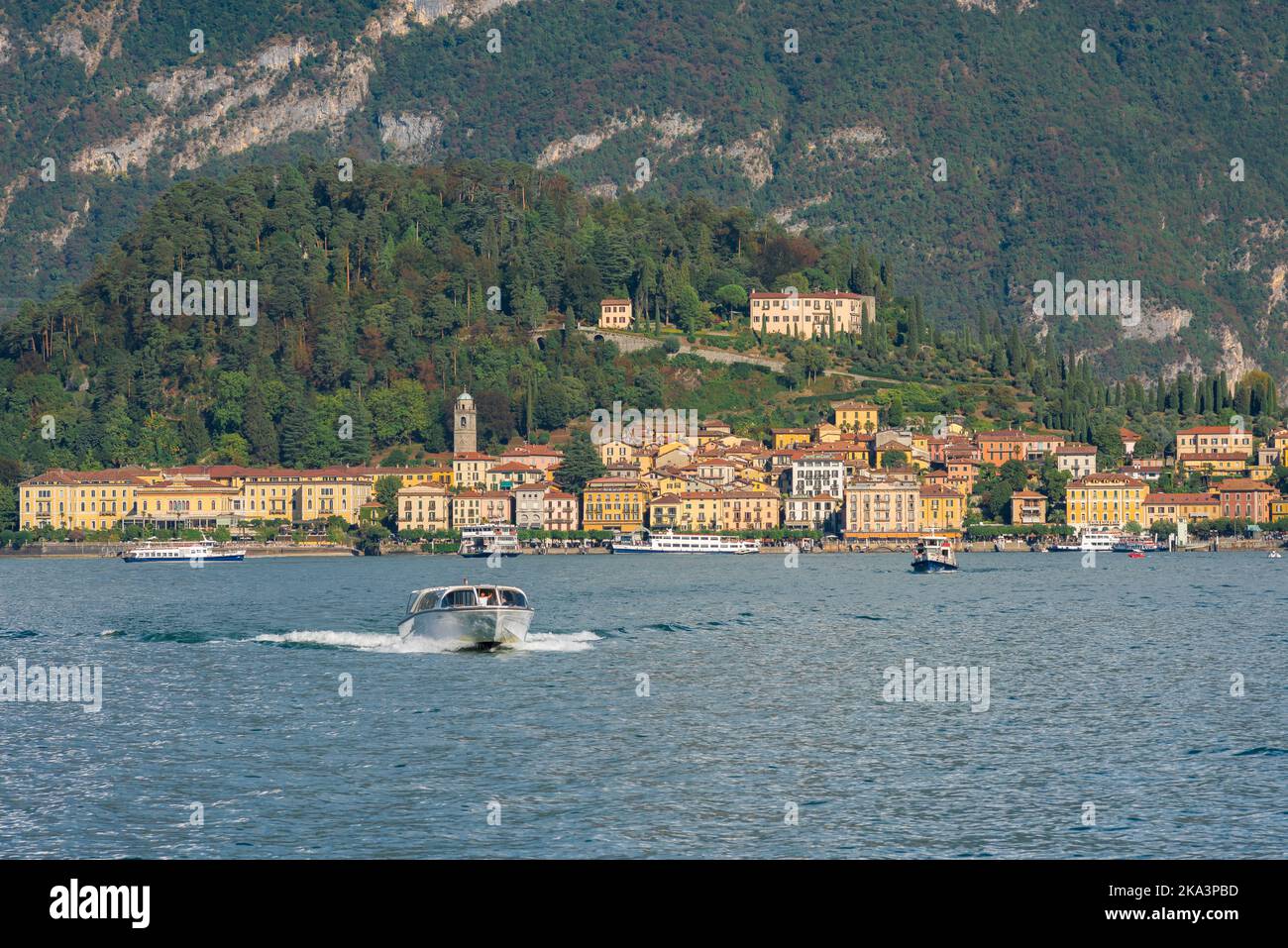 Lago italiano panoramico, vista in estate di un motoscafo che attraversa il lago di Como sullo sfondo della pittoresca cittadina lacustre di Bellagio Foto Stock