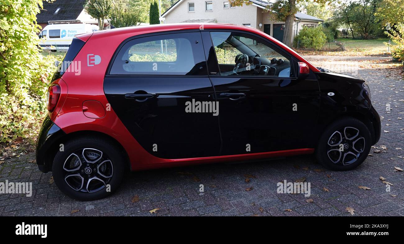 Itterbeck, Germania - Ott 16 2022 Vista laterale su un grazioso Smart per quattro EQ Electric Drive nei colori nero e rosso Foto Stock