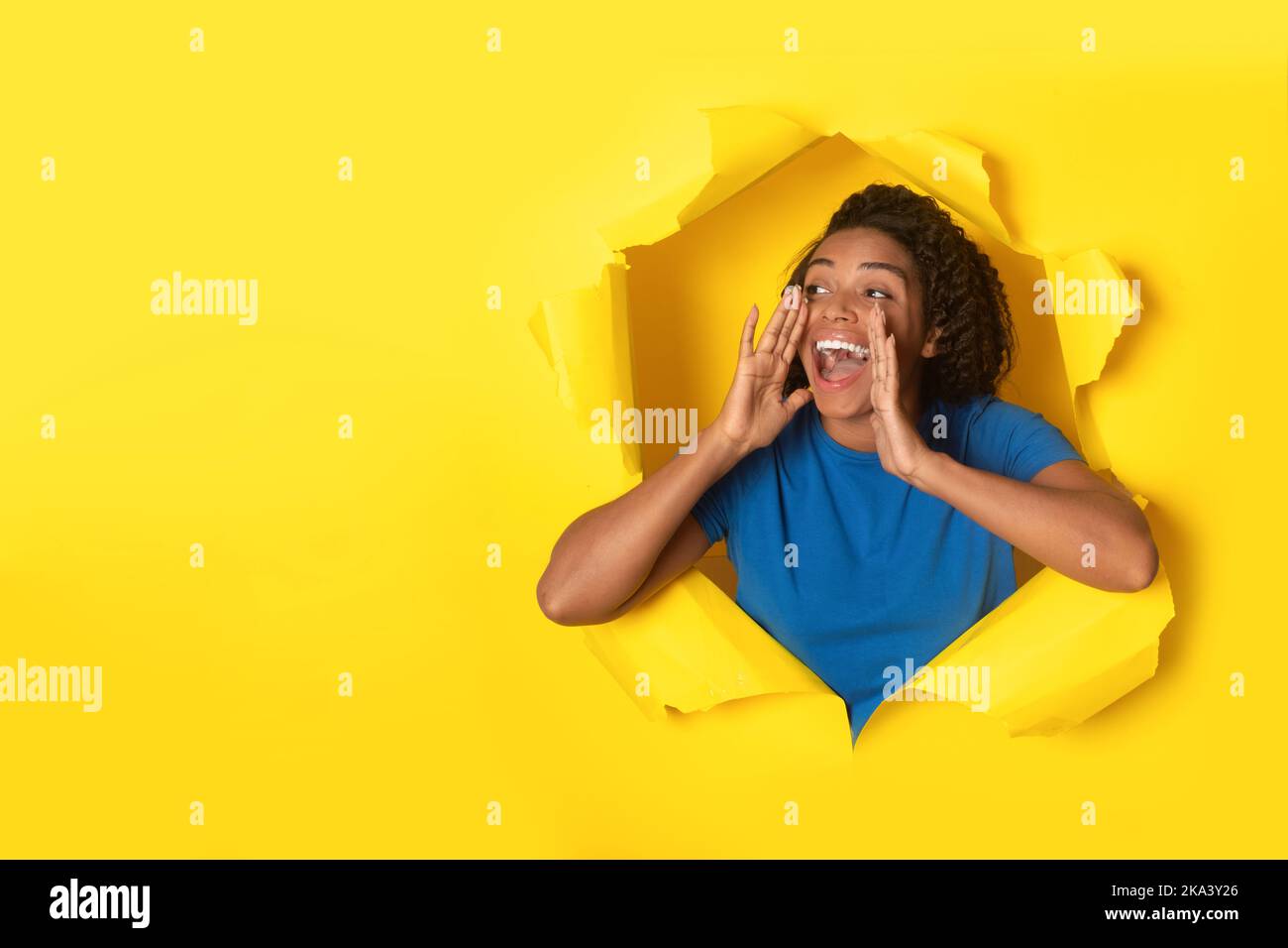 Donna nera felice gridando posa in carta gialla strappata sfondo Foto Stock