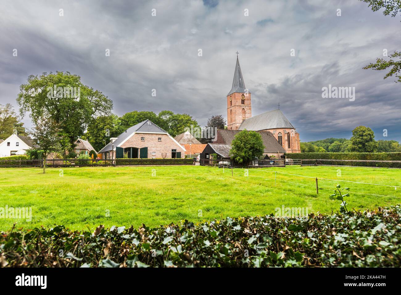 Estate paesaggio urbano Drents villaggio Rolde con Jacobuskerk e le fattorie viste dalla Hunebedweg su uno sfondo di orrido Wee con cielo grigio scuro Foto Stock