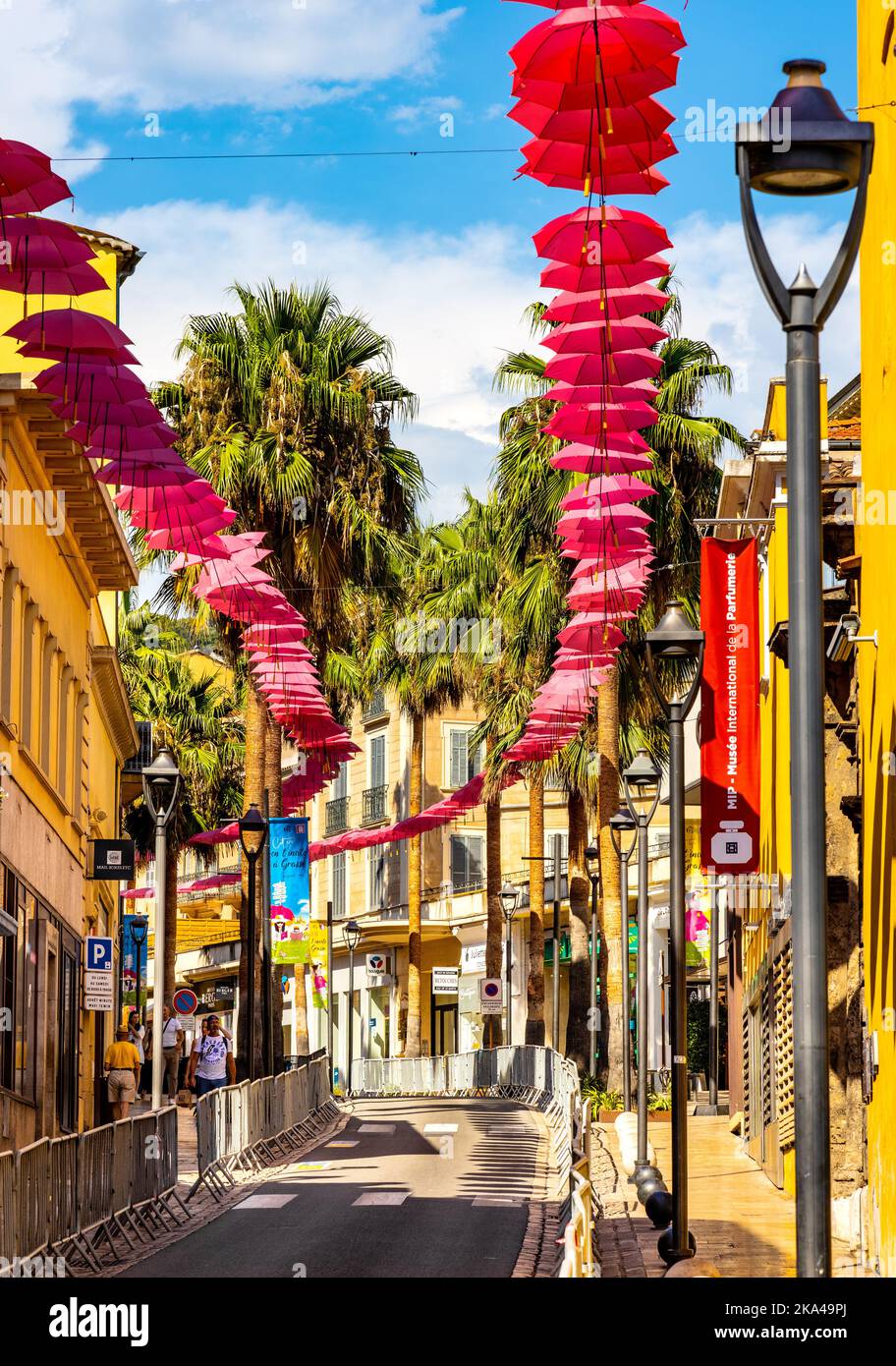 Grasse, Francia - 6 agosto 2022: Boulevard du Jeu de Ballon strada decorata con ombrelloni rosa nel centro storico della città di profumeria di Grasse Foto Stock