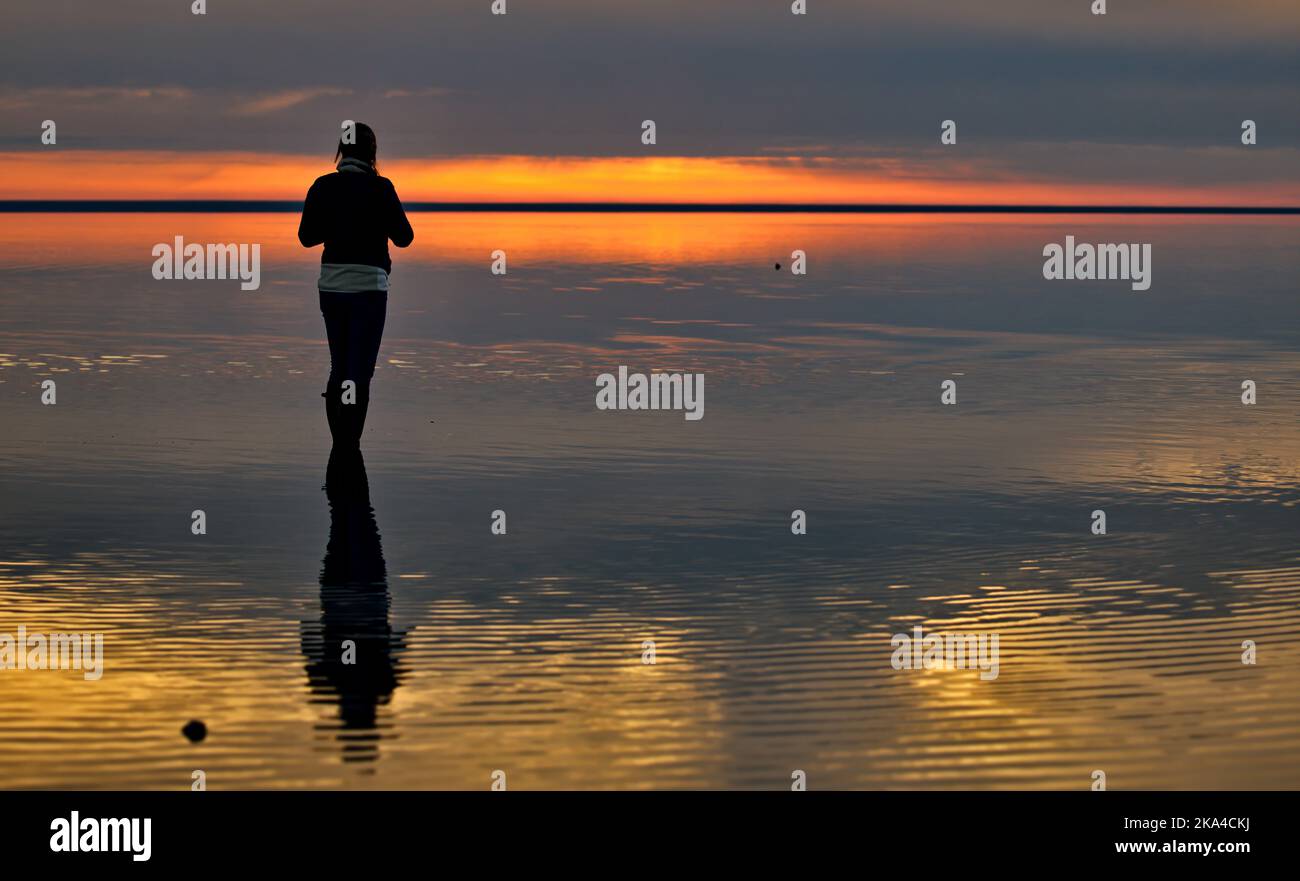 Una giovane donna che gode di una splendida vista sul mare durante il tramonto panoramico sul lago Elton, Russia Foto Stock