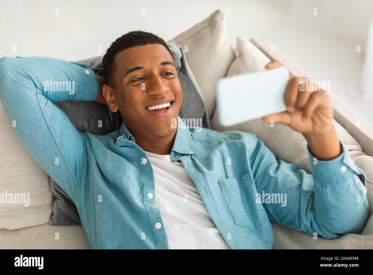 Felice ragazzo americano africano millenario hanno videochiamata, guardando divertente video su smartphone in tempo libero Foto Stock