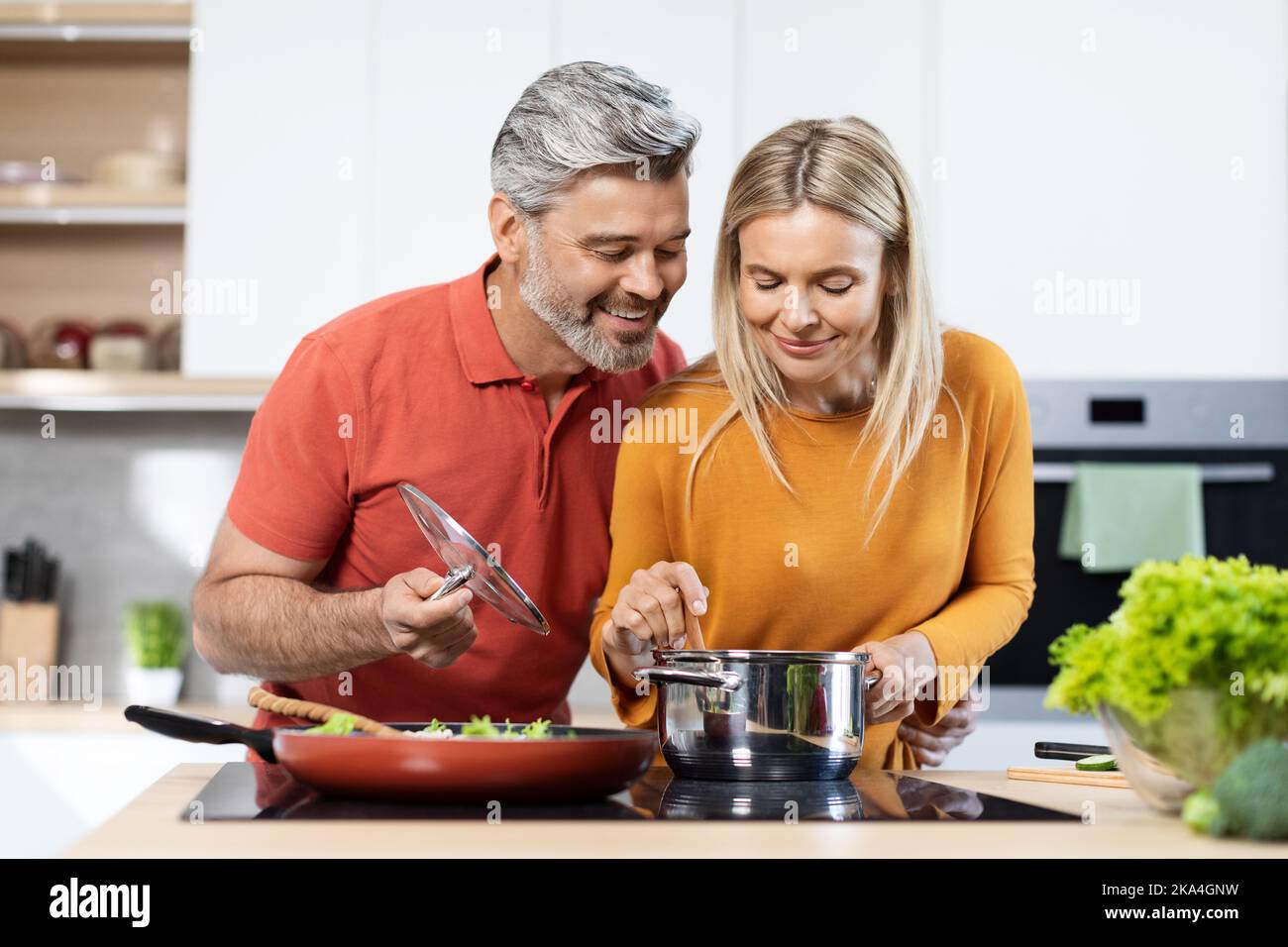 Bell'uomo e donna di mezza età che cucinano insieme in cucina Foto Stock