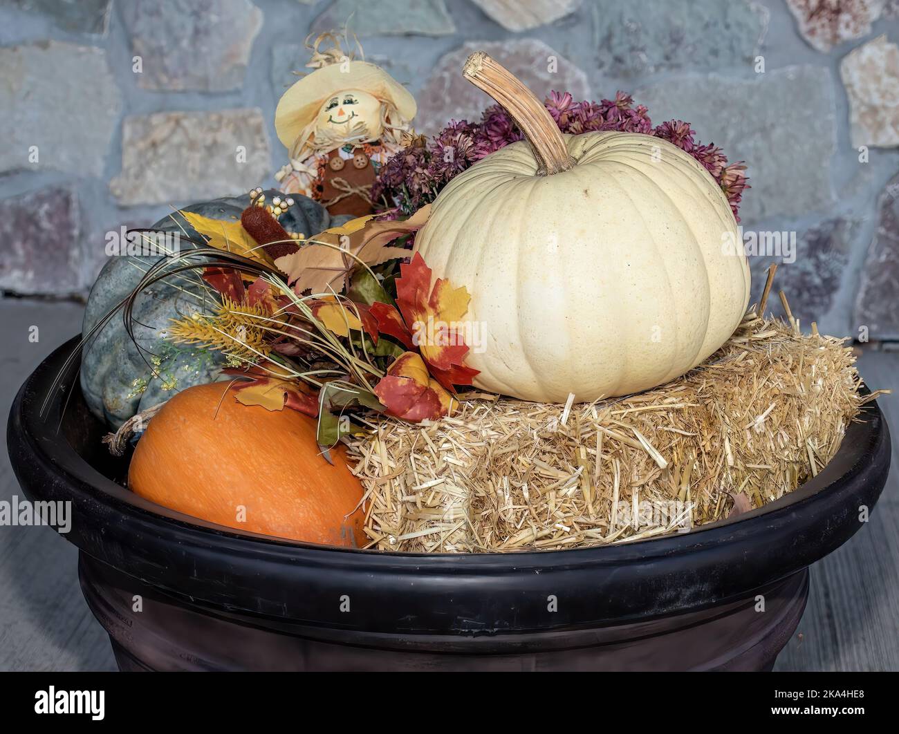 Decorazione autunnale in un vaso di fiori con fieno, zucche, una zucca bianca e una bambola di scarabei per celebrare l'autunno e Halloween. Foto Stock