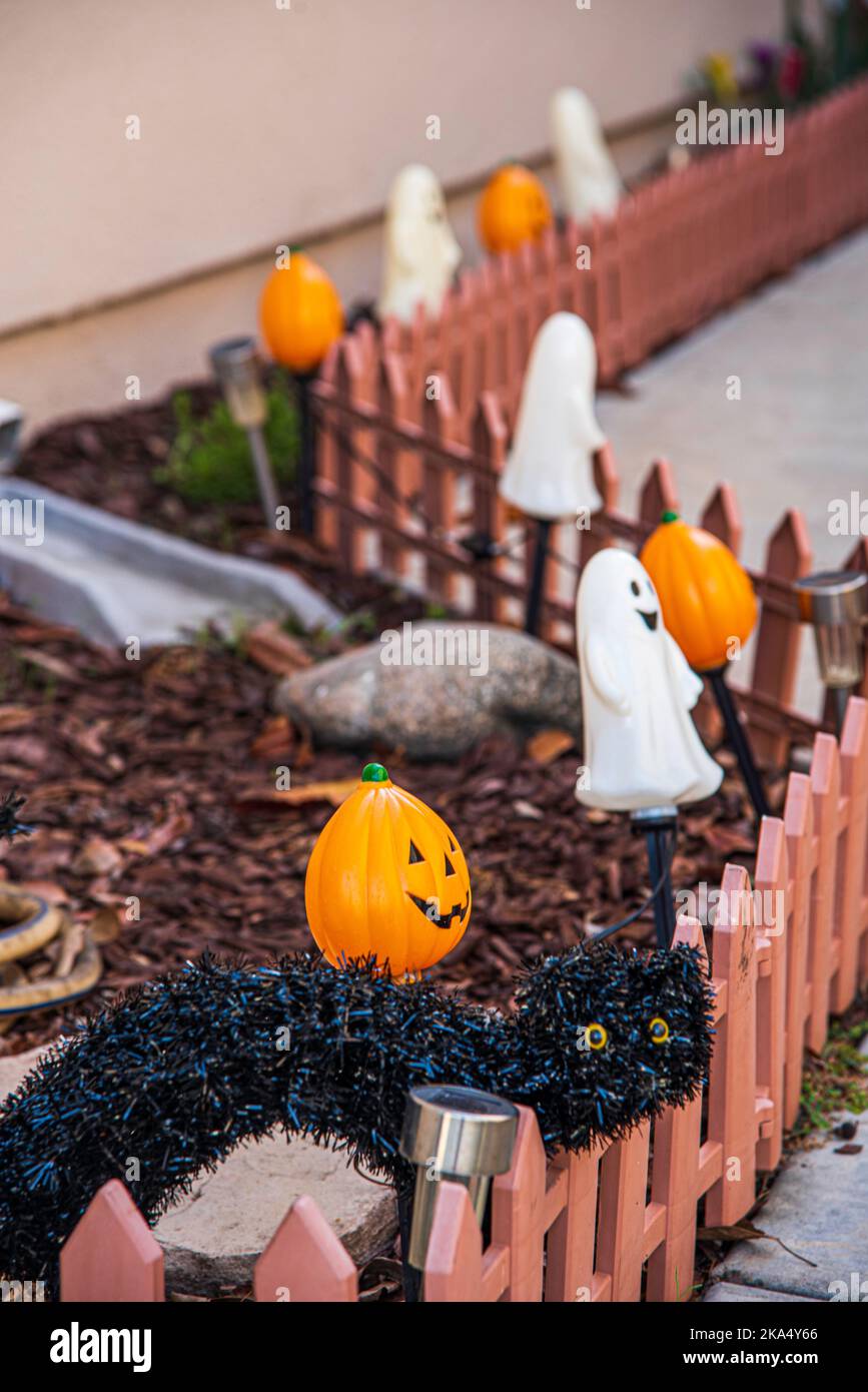Decorazioni di Halloween costituite da una dispersione di jack o' lanterne e fantasmi lungo una linea di recinzione di un cortile di una casa suburbana. Foto Stock