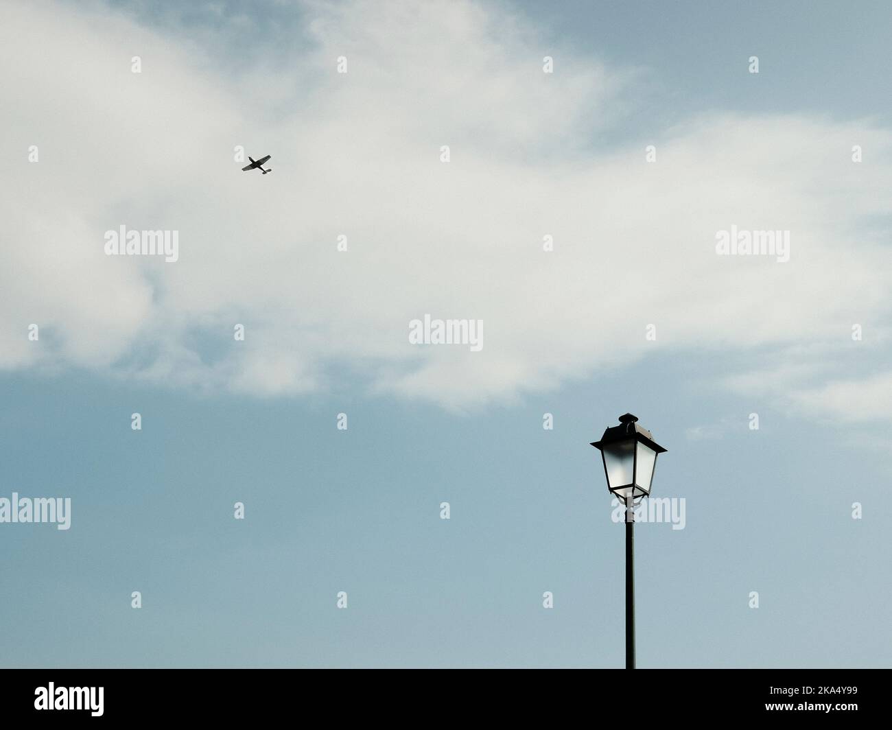 Lanterna nera sotto il cielo blu con aereo volante Foto Stock