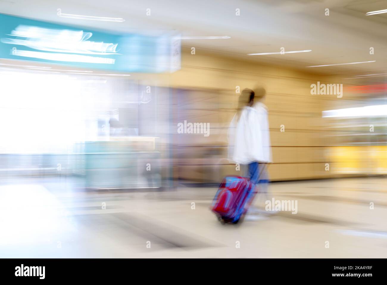 Una donna in viaggio sfocata con una valigia Foto Stock