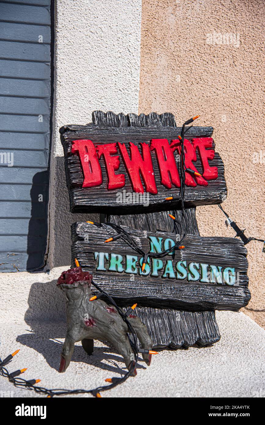 Un segno in rosso dice 'attenzione 'e sotto un altro segno dice, 'nessun trasgressione.' Decorazioni di Halloween di fronte a una casa a Placentia, California, USA. Foto Stock