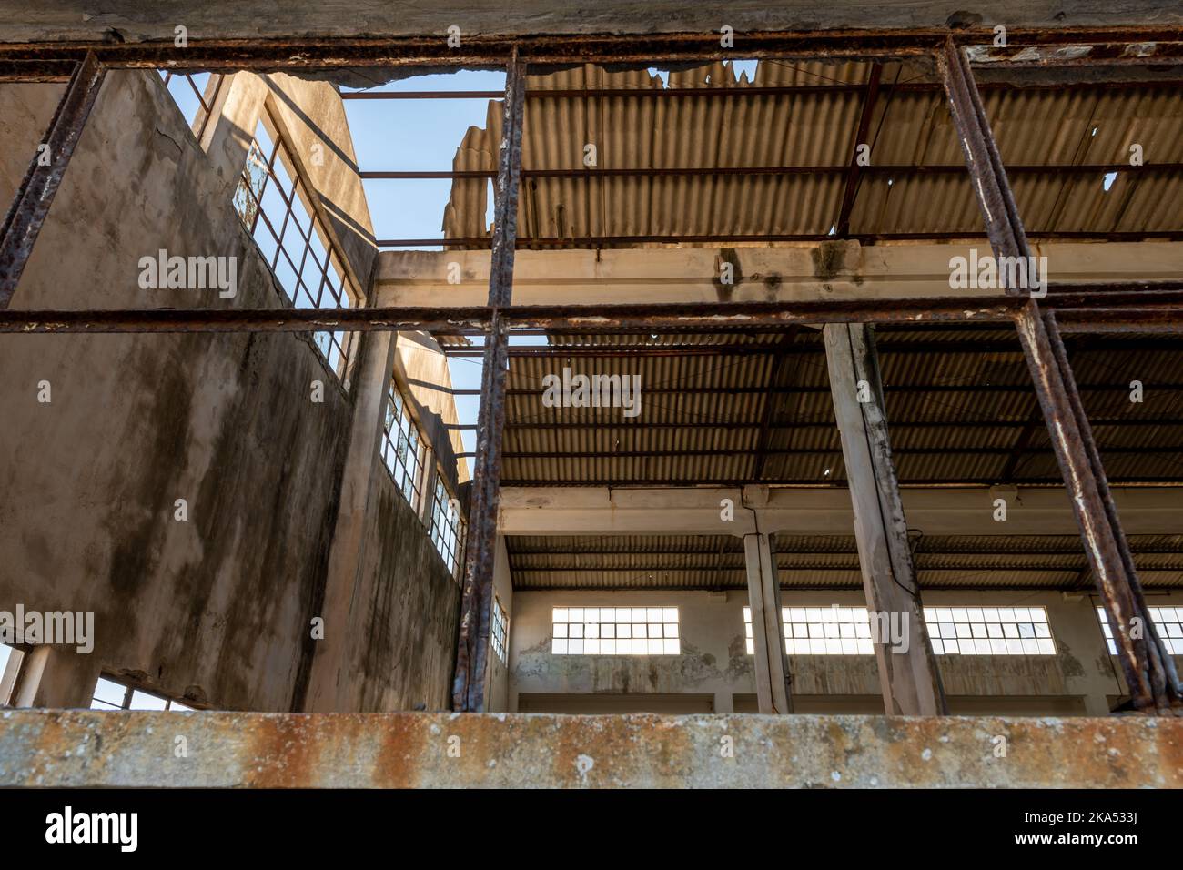 Vista interna di una fabbrica abbandonata che mostra la rottura del tetto in amianto. Foto Stock