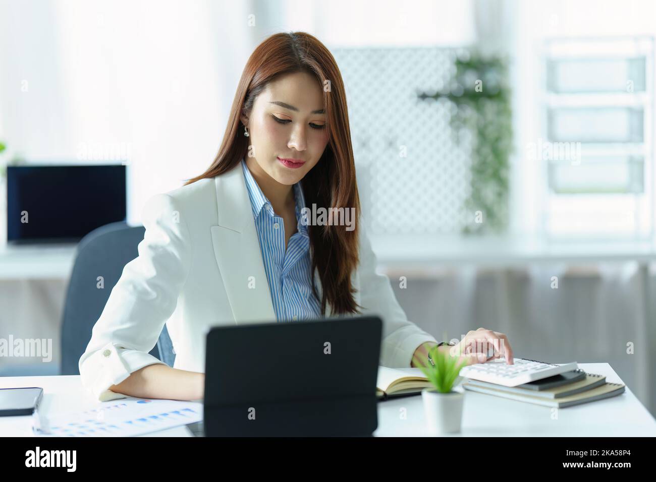 Ritratto della donna d'affari asiatica o del proprietario di affari usando il calcolatore del tablet, calcolatore di preventivo e pianificatore di vendita dell'ufficio. Foto Stock