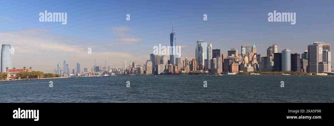 Vista panoramica dei grattacieli di New York City (Lower Manhattan) e di Ellis Island dall'acqua, USA Foto Stock