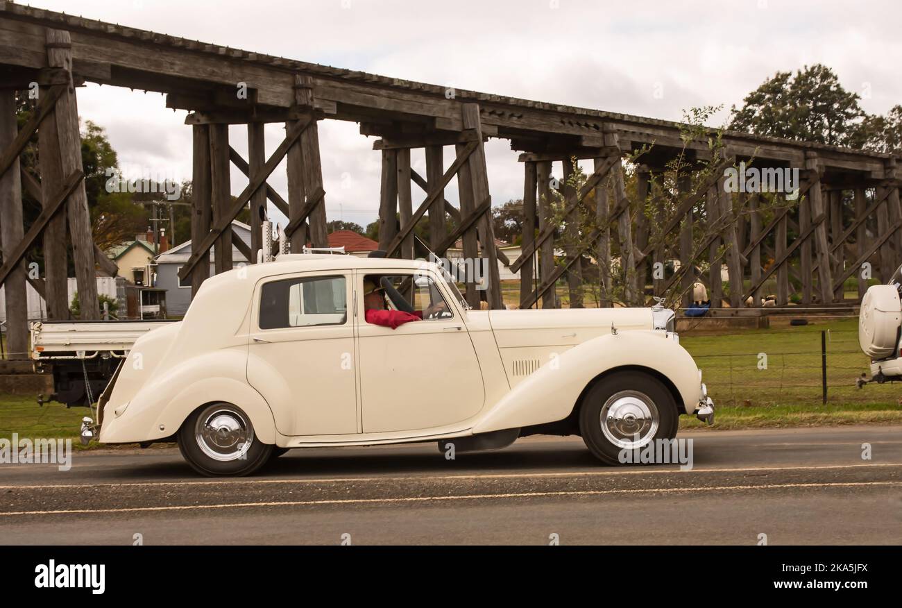 Un berlina c1950 a quattro porte Mark VI Bentley bianco che passa un vecchio viadotto ferroviario a Manila Australia. Foto Stock