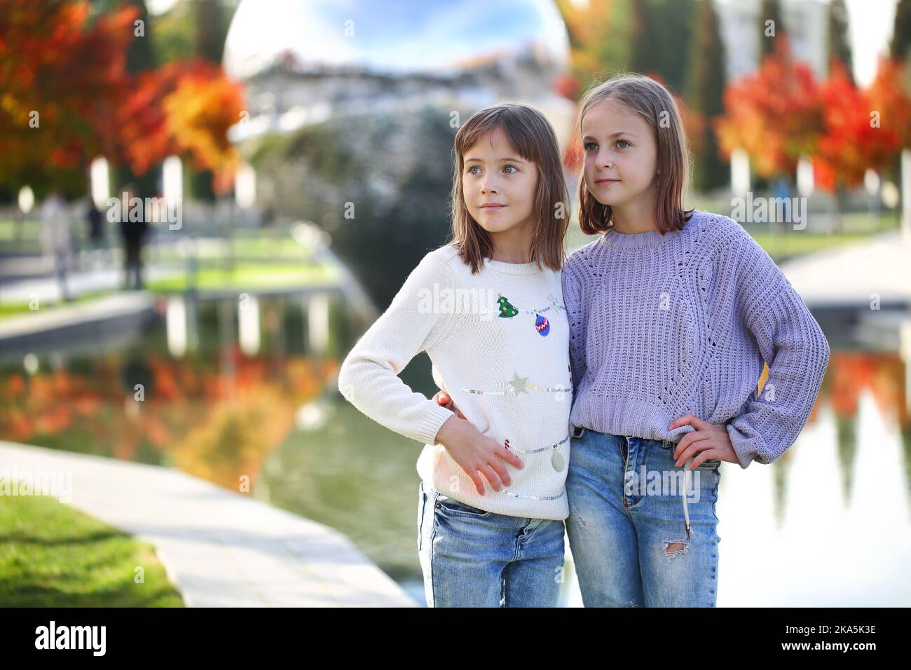 Due ragazze si trovano vicino a uno stagno nel parco Foto Stock