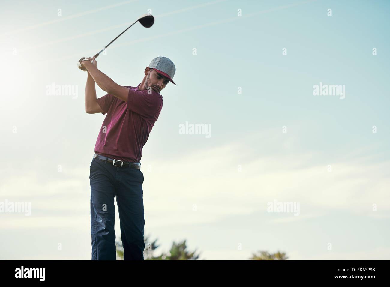 Guardando come un pro. Un golfer maschio giovane messo a fuoco circa oscillare e giocare un colpo con il suo randello di golf fuori su un corso. Foto Stock