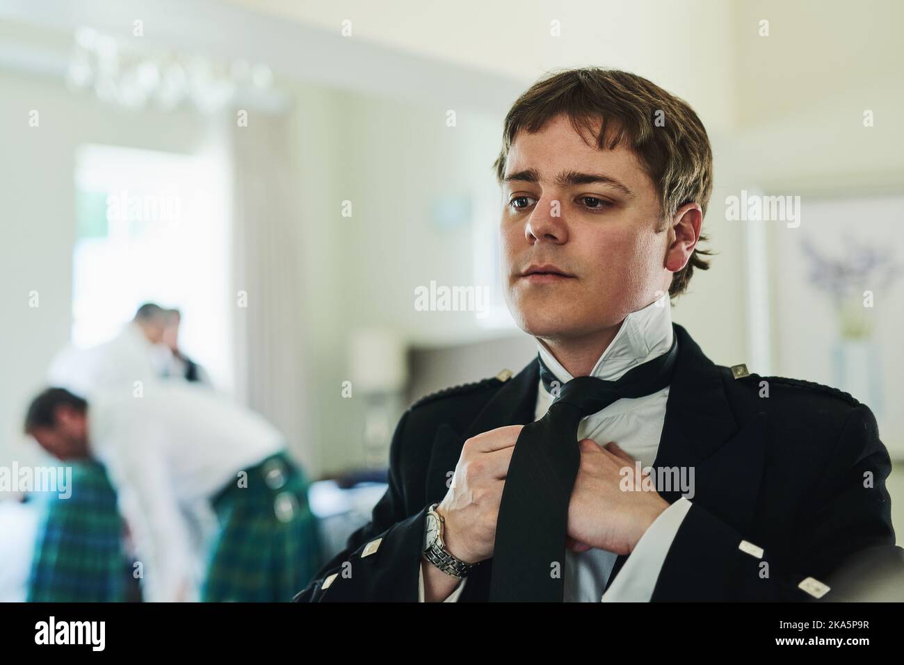 Oggi devo assicurarmi di avere un aspetto migliore: Un giovane uomo sicuro che si piega una cravatta mentre si guarda in uno specchio per prepararsi a un matrimonio. Foto Stock
