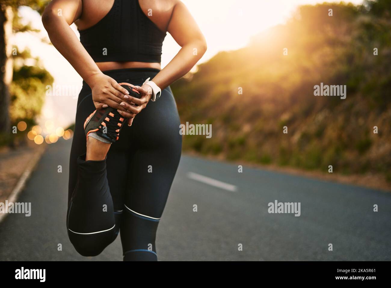 Il riscaldamento fa la differenza: Una giovane donna irriconoscibile che si allunga prima della sua corsa. Foto Stock