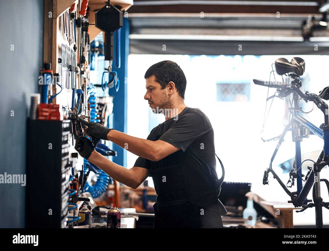 Theres niente che doesnt sappia circa riparazione della bicicletta. Un uomo che lavora in un negozio di riparazione della bicicletta. Foto Stock