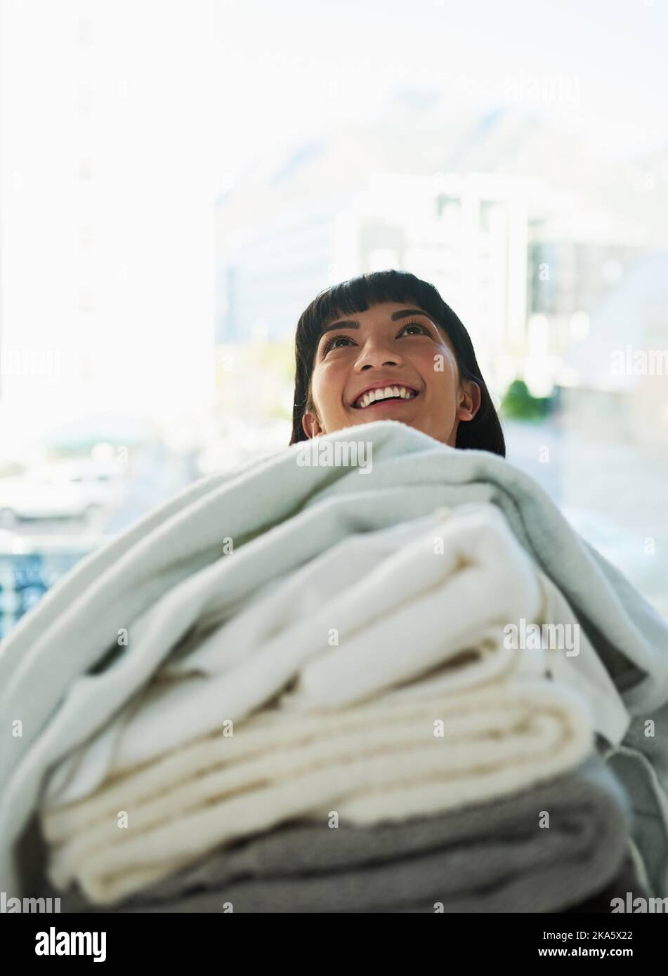 Lavanderia è finalmente fatto. Una giovane donna che trasporta un mucchio di asciugamani il giorno di lavanderia a casa. Foto Stock