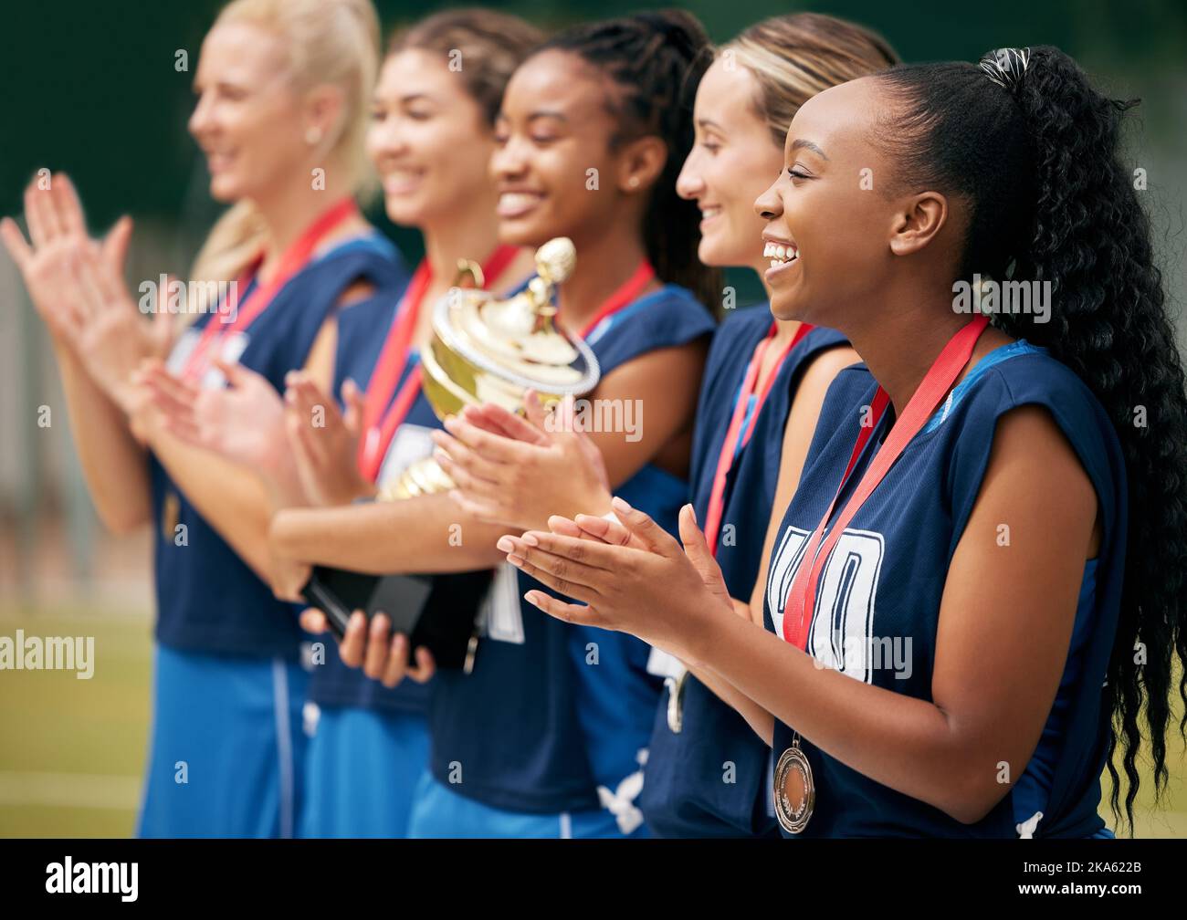 Trofeo, sport e donne che battono le mani per il successo, la motivazione o la celebrazione nel gioco di netball professionale. Squadra vincente, di supporto e atleta con Foto Stock