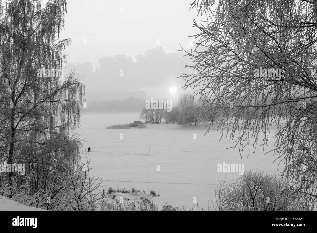 Bellissimo paesaggio invernale. Un pescatore nella neve. Tramonto sul fiume. Foto di alta qualità Foto Stock