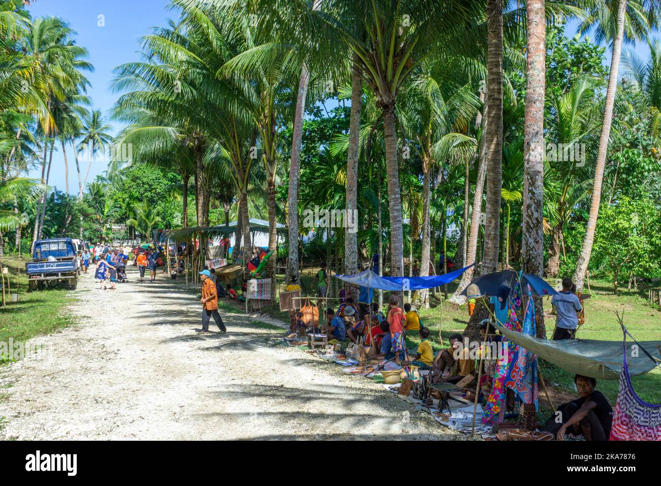 Gli abitanti del villaggio si allineano sulla strada vendendo artigianato e souvenir per visitare i passeggeri delle navi da crociera. Isola di Kiriwina Papua Nuova Guinea. Foto Stock