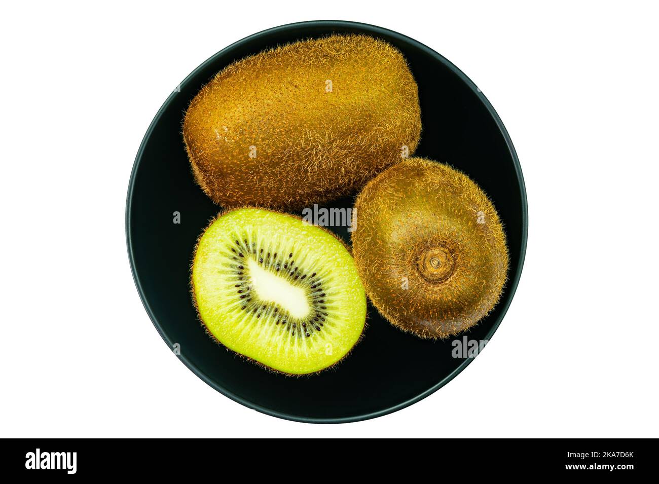 Vista dall'alto, piatto di frutta fresca matura dolce kiwi, kiwifruit intero e mezzo in ciotola nera in ceramica isolata su sfondo bianco con percorso di ritaglio. Foto Stock