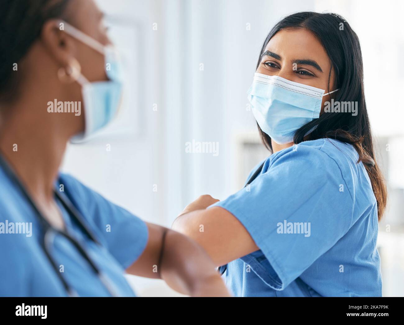 Covid, donne e medici gomito saluto in maschera chirurgica in ospedale o clinica durante la pandemia. Lavoro di squadra, operatore sanitario e medico Foto Stock