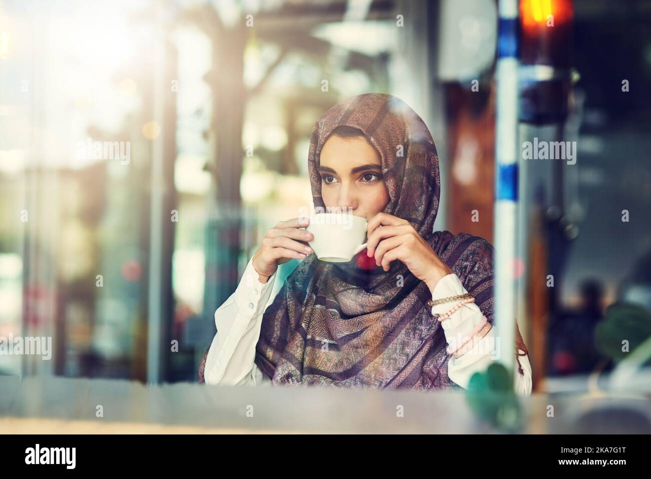 Sabato mattina lento sorseggiando un caffè, una giovane donna che ha una tazza di caffè in un bar. Foto Stock