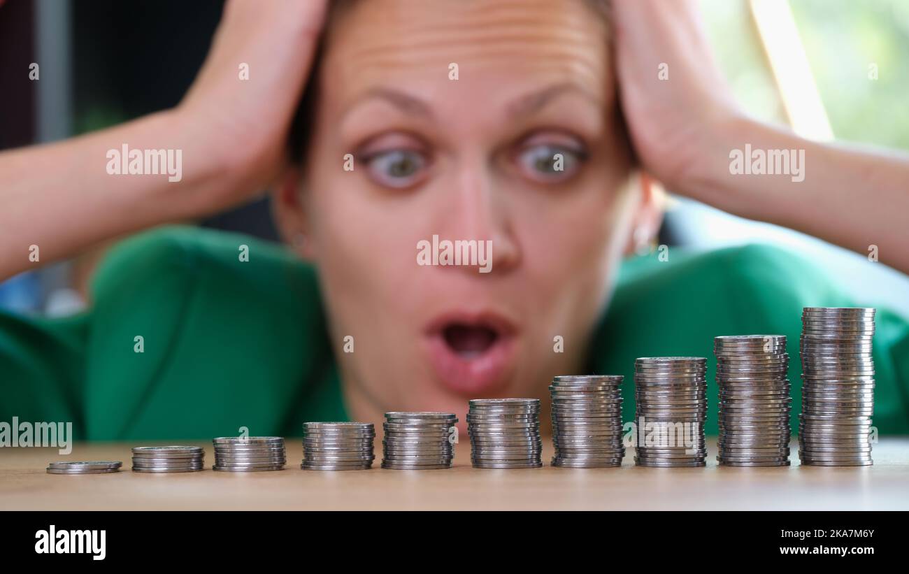 Donna che guarda mucchi di monete e che tiene in testa Foto Stock