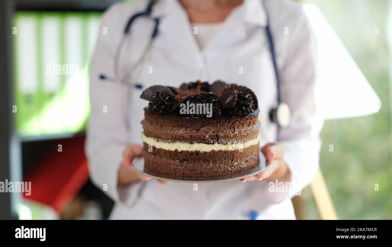 Donna nutrizionista che tiene in mano grande torta al cioccolato Foto Stock