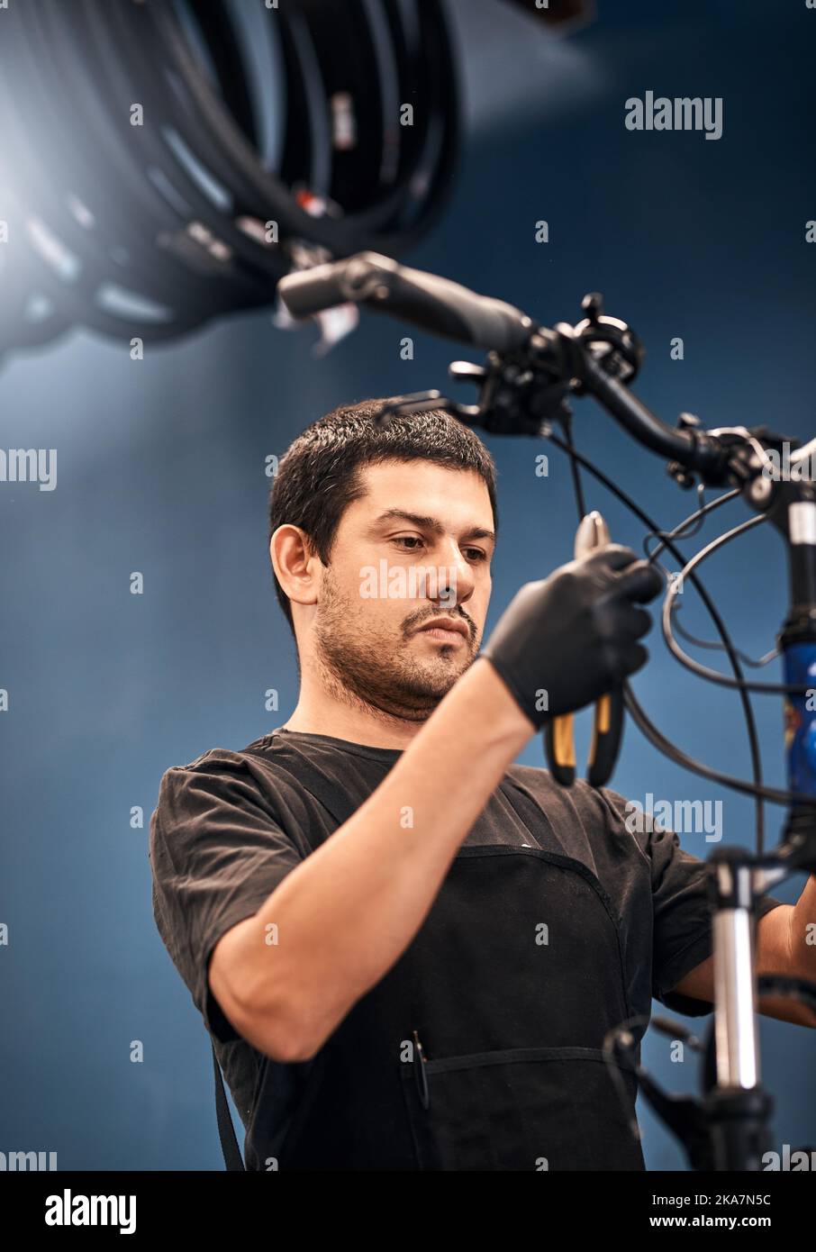 Il vostro va al tipo per la riparazione eccellente della bicicletta. Un uomo che lavora in un negozio di riparazione della bicicletta. Foto Stock