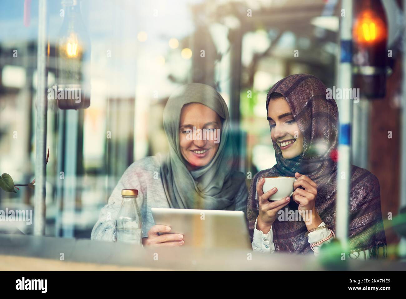 Stare al passo con le tendenze dei social media con un amico. Due donne che utilizzano un tablet digitale insieme in un bar. Foto Stock